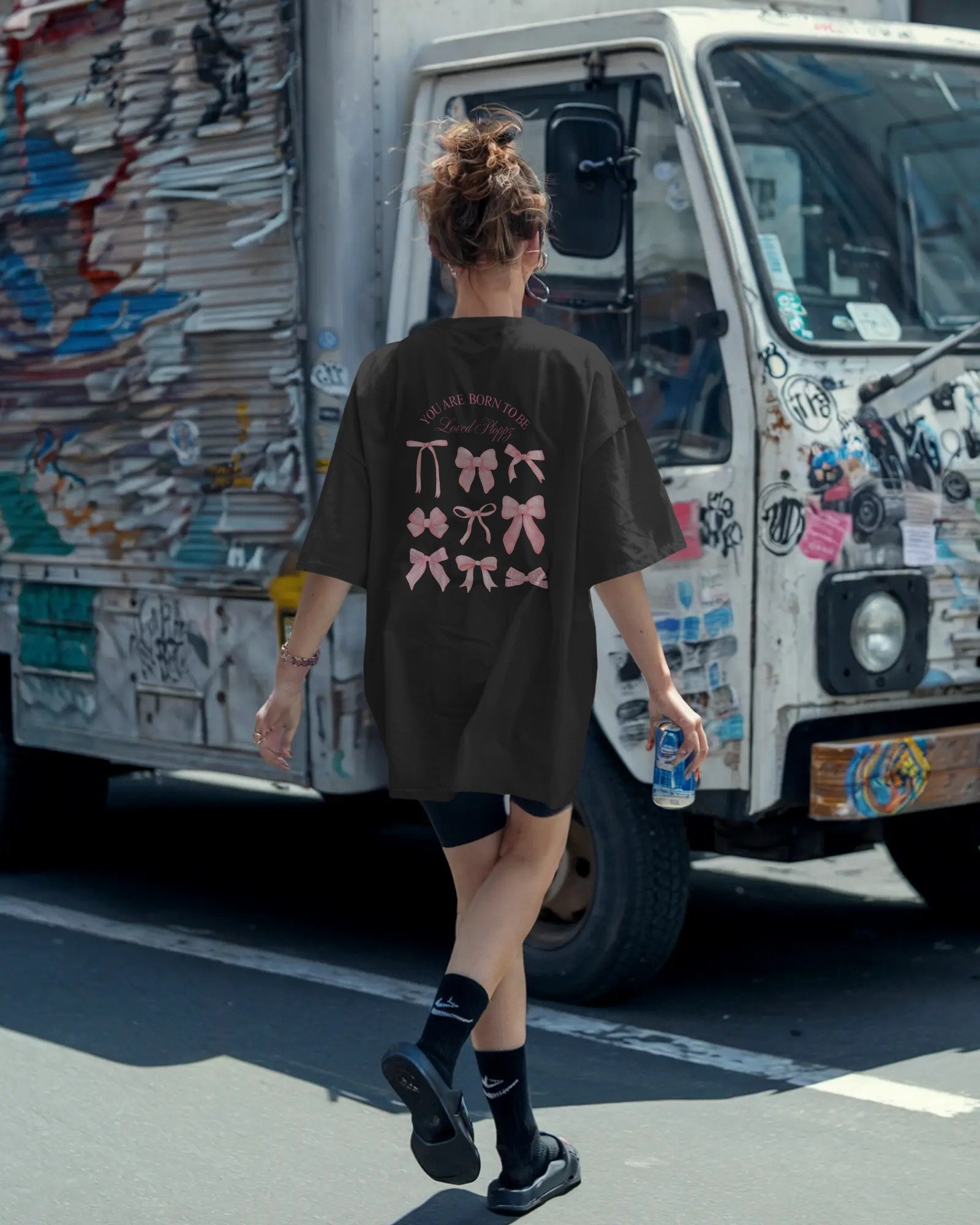 urban-streetwear-boxy-t-shirt-mockup-female-model-walking-with-can-in-hand-in-front-of-graffiti-truck-edgy-casual-scene-01741